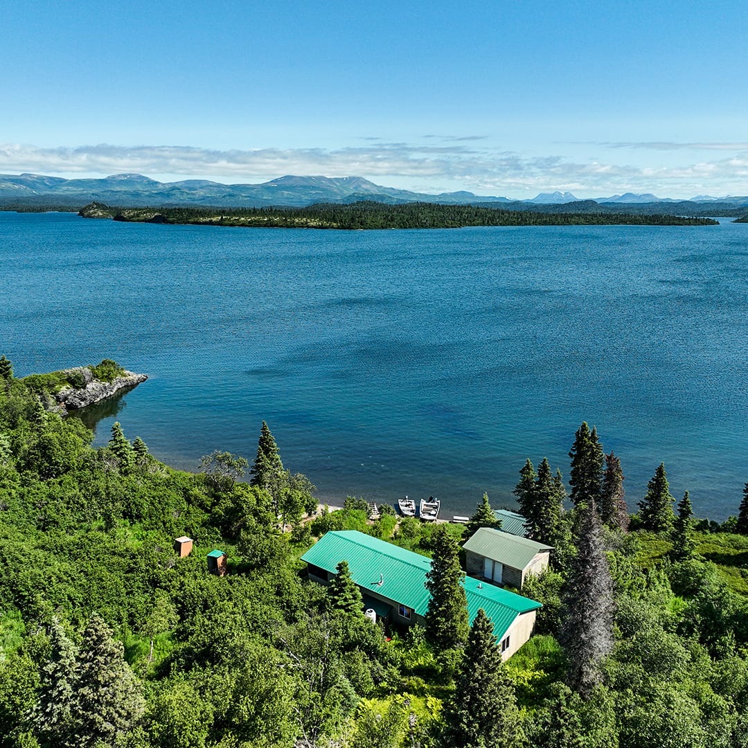 Drone photo of Legend Lodge on the shoreline of Lake Iliamna with mountains across the water