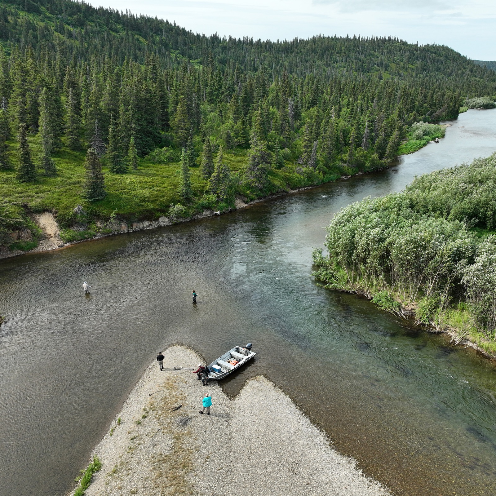 Drone view of anglers and a boat on a gravel bar of a clear Alaska river