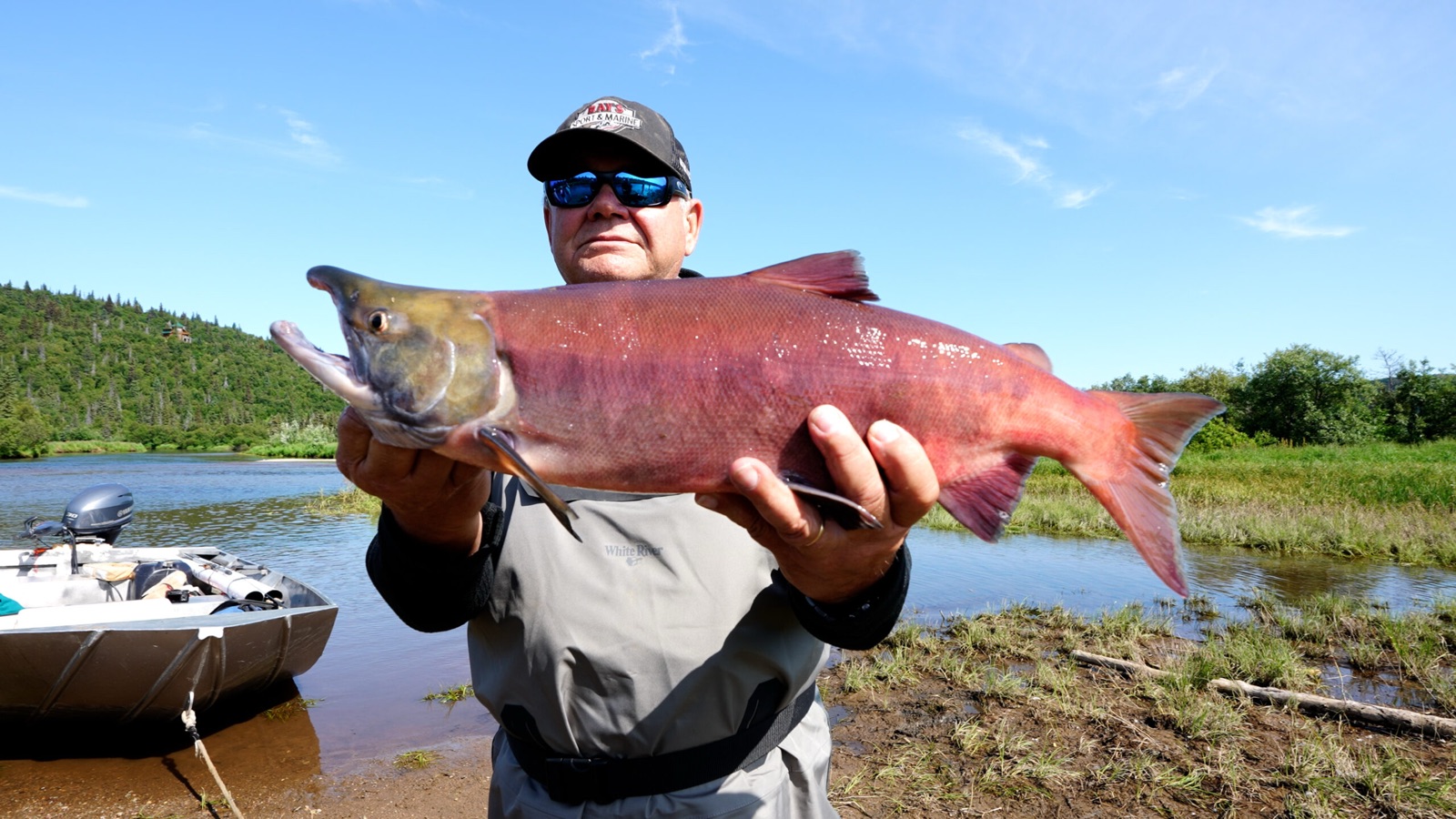 Angler holding a large red sockeye salmon beside the boat